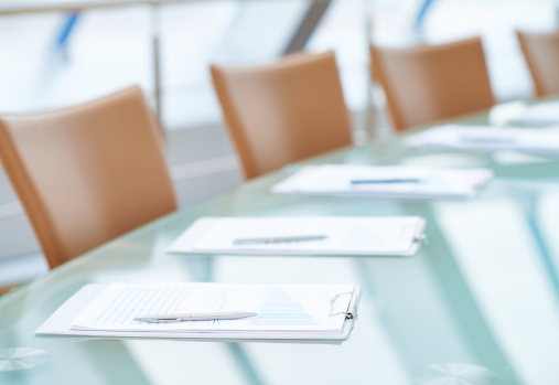 a boardroom table set up with AGM reports and a pen at each spot