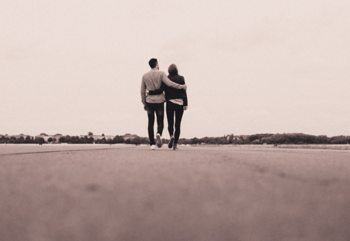 couple walking arm in arm down a paved road