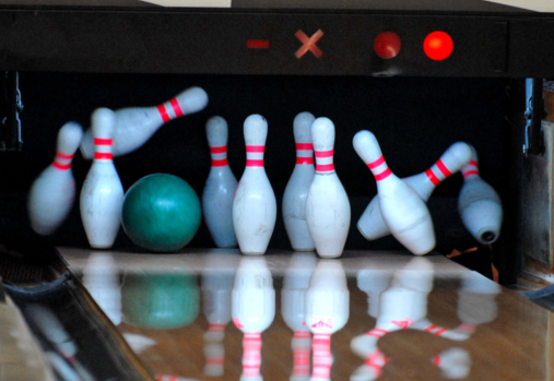 bowling pins being hit by a green bowling ball