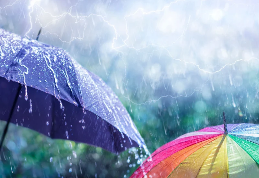 a blue and multicoloured umbrella in the rain with lightning in the background