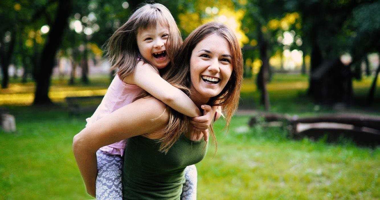 mother playing with special needs child, smiling
