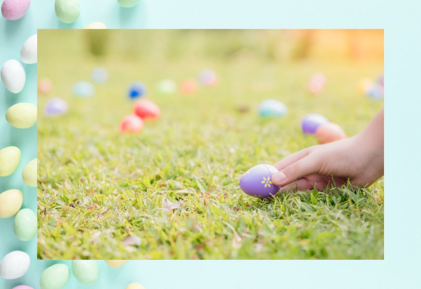 A hand picking up an Easter egg from the grass.