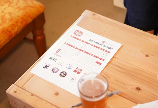 A drink on a table with a pen and game sheet