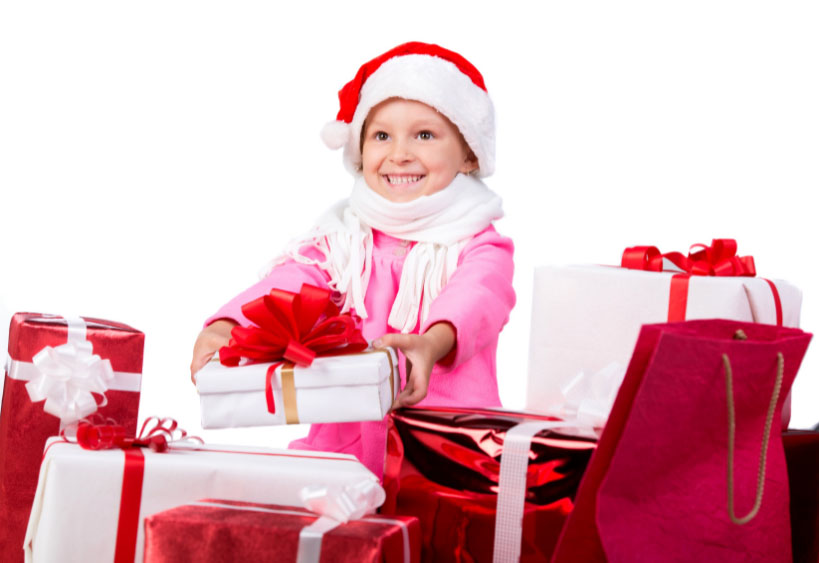 A little girl giving a holiday gift, surrounded by many gifts