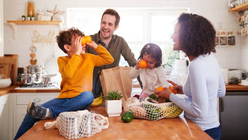 family unpacking grocery bags and kids playing with oranges