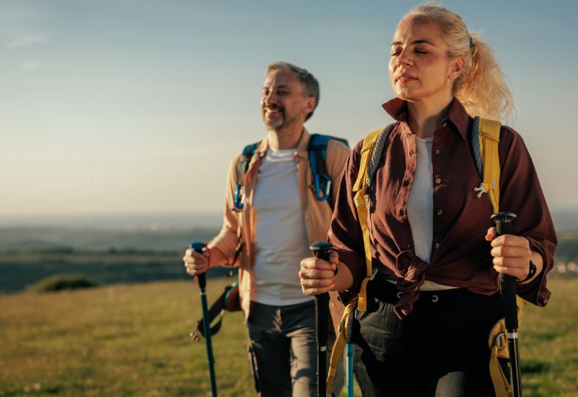 two adults walking with walking sticks closing their eyes to breath