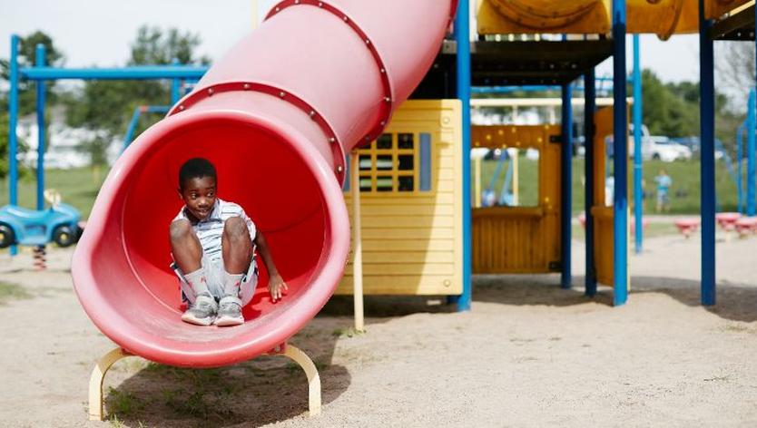 A young boy coming down a red slide