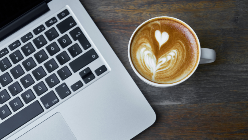 coffee cup standing next to laptop