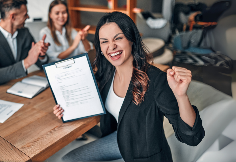 woman holding up a contract and cheering