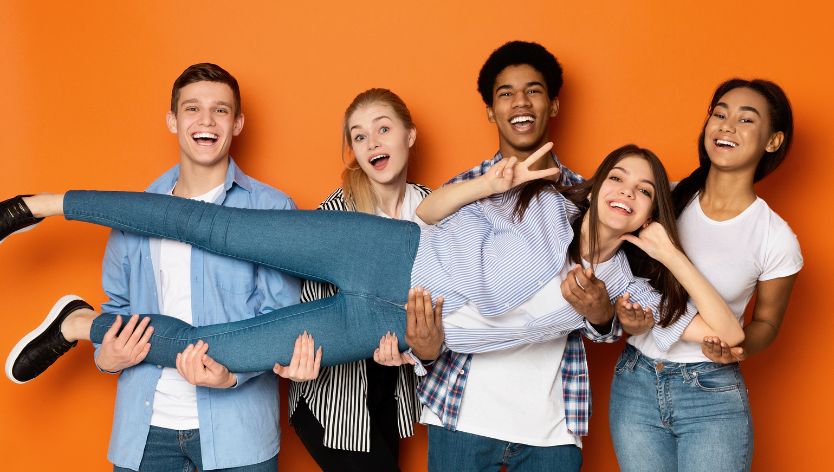 five youth gathered and one girl being carried by them