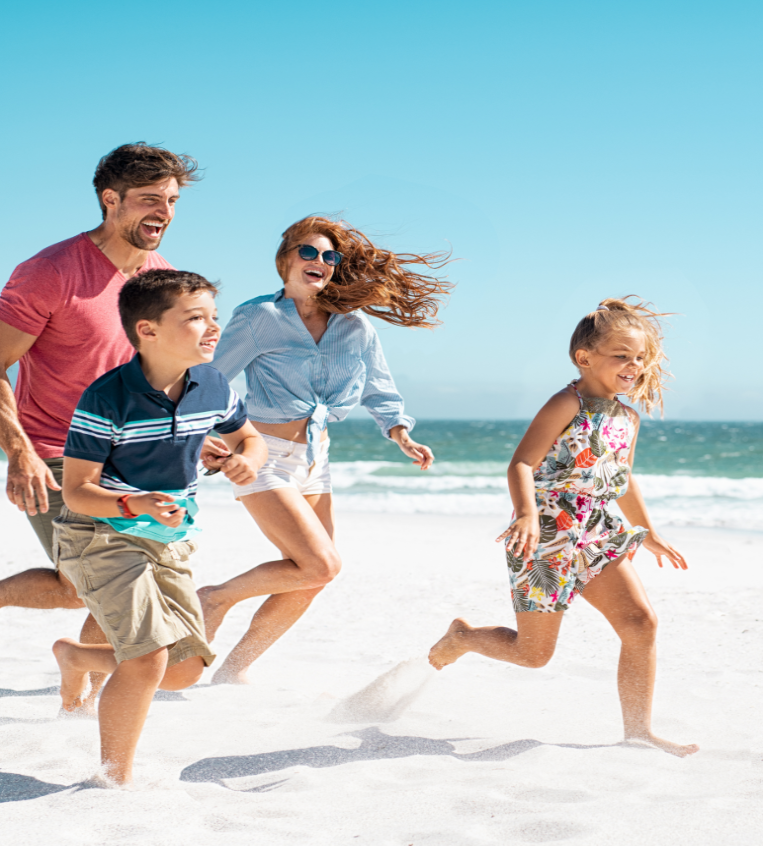 Parents with their two children running on the beach