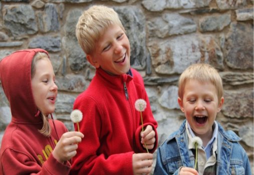 3 children laughing and holding dandelions